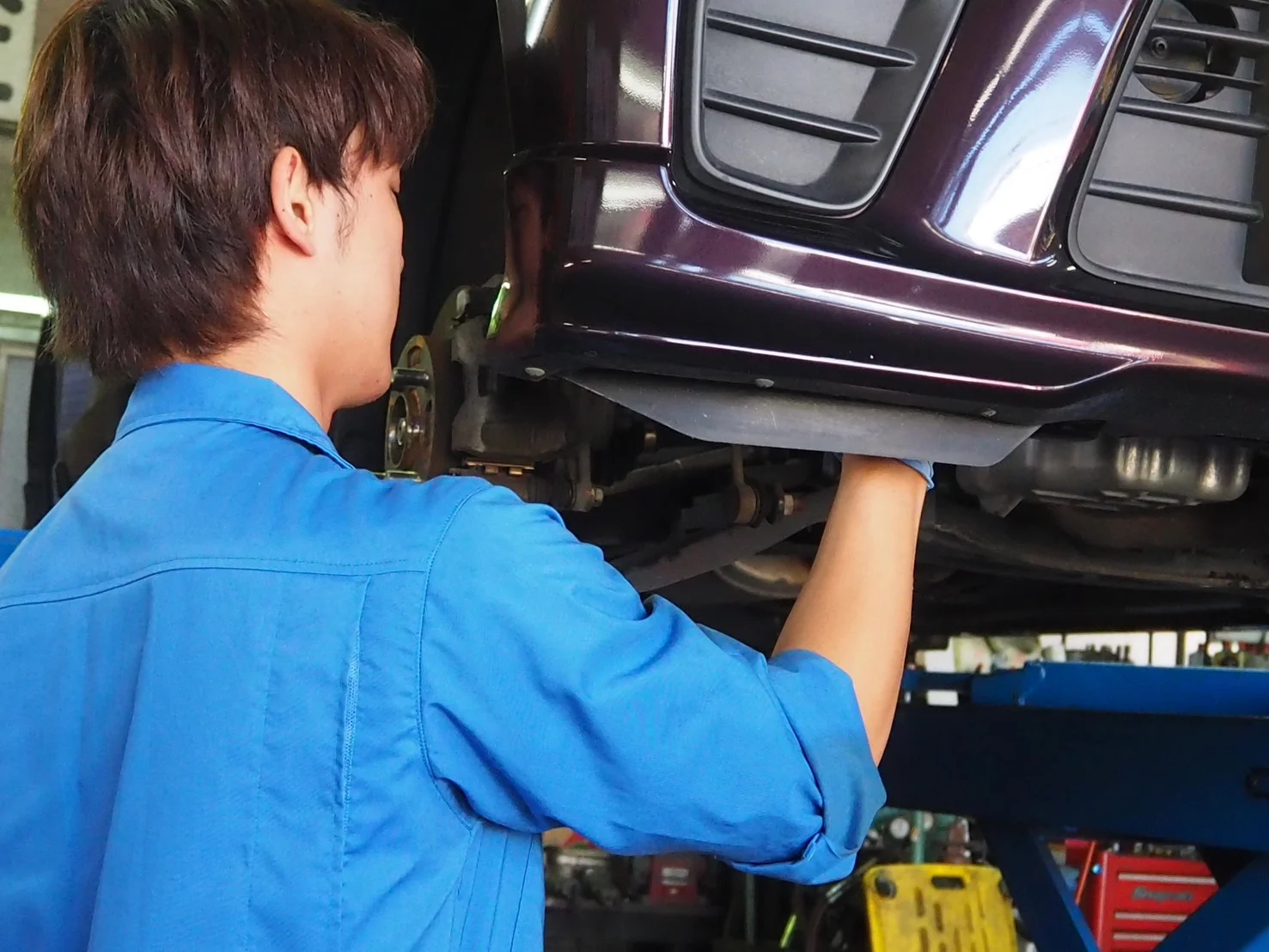 リフトで上げた車両を整備する宮本さん